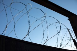 Barbed wire rings on fence. Protected area. Steel wire protection.