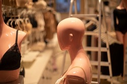 Mannequin of girl is viewed from side. Head without hair. Figure of man made of plastic. Details of clothing store.