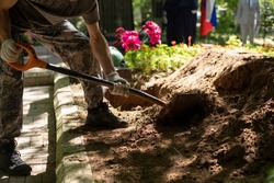 Man digs grave. Guy with shovel digs ground. Funeral details. Work in cemetery.