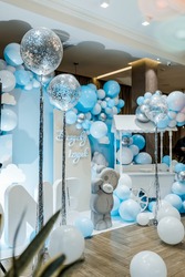 Festive background decoration letters saying one and white blue balloons in studio. Baby birthday theme with teddy bear. Baby Boy. Cake Smash first year concept. birthday greetings. Candy bar.