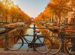 Evening over beautiful Amsterdam canals in autumn. Bicycles parked at the bridges in the foreground 