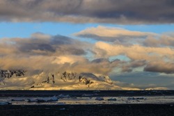Sunrise illuminates low cloud over spectacular coastal mountains of the Antarctic Peninsula