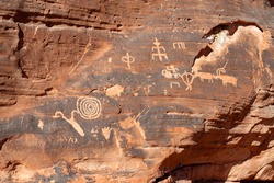 Atlatl Rock Petroglyph Panel at Valley of Fire State Park in Nevada. Featuring rock art pictographs of bighorn sheep, stick figures, spirals, and other designs.