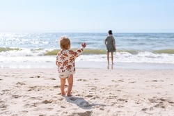toddler calling his mother at the beach. Conceptual photo of mother-child relationship, separation anxiety, and attachment theory.