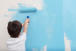 child paints with roller a wall blue. The concept of world peace. Blue sky overhead. End of quarantine. Freedom.Start from scratch. Repair