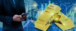 Gold stock market exchange concept. Businessman using smartphone with gold bars and data analyzing in forex charts background.