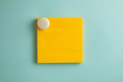 Yellow sticky note paper with white circle magnet isolated over blue pastel background.,cliping path include sticky note.,Cut out stationery or memo pad.