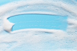 Soap foam on blue surface. Shampoo, shower gel, mousse bubbles.  Bath hygiene background. Abstract cleansing foam texture
