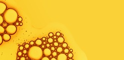 Oil drops with bubbles on yellow background. Cosmetic oil serum detail. Abstract orange color liquid texture macro