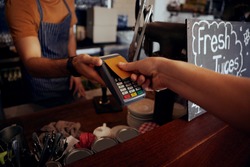 Female hands holding card against nfs payment machine to make payment for purchase in cafe