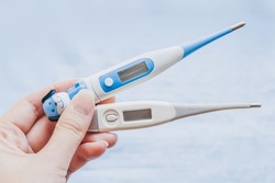 female hand holding electronic baby and adult thermometer. diagnosis of diseases. Types of thermometers. Health, medicine epidemic, pandemic