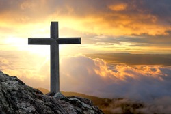 cross crucifixion on a mountain cliff rock With a sunset background