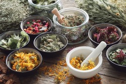 Mortar, bowls and jars of dry medicinal herbs on table. Healing herbs assortment. Alternative medicine.