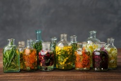 Bottles of essential oil or infusion of medicinal herbs and berries - rosemary, calendula, tansy, thuja, thyme, bergamot, chamomile.  Healing plants, medicinal herbs and berries. Alternative medicine.