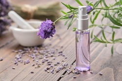 Spray bottle of lavender essential oil. Scented lavender water, serum, flavored water. Lavender flowers on background. Aromatherapy. Natural cosmetic beauty care product. Alternative herbal medicine.