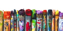Row of artist paintbrushes closeup on white. Artistic brushes smeared with paints on white background.
