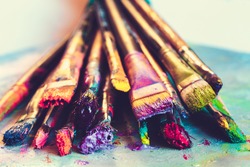 Artist paintbrushes with paint closeup on artistic canvas. Retro toned. Selective focus.