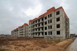 Construction of low-rise monolithic brick block of houses according to standard design. Empty construction site - project is not built, . Unfinished construction. Four storey country house in suburbs.