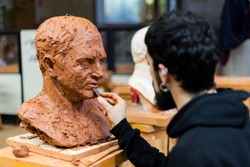 Sculptor finishing a bust of cicero clay in an art studio