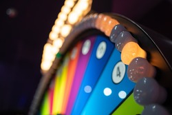 Arcade gambling machine up close. Giant wheel with colorful sections and lights.