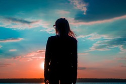 Young woman watching at sunset background
