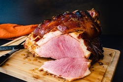 Bourbon Orange Glazed Ham on a Bamboo Carving Board: Sliced bone-in glazed ham on a wooden cutting board