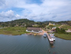 Drone aerial view of Fordlandia city skyline in Amazon rainforest, Brazil. Tapajos river and historic water tank tower. Wooden boats in riverbank.