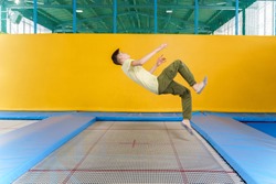 Teenage boy jumping on trampoline park in sport center 