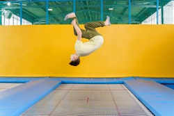 Teenage boy jumping on trampoline park in sport center 