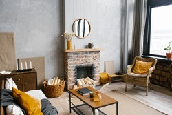 A coffee table by the fireplace of a country house and a wicker chair in the living room of the house in the Scandinavian style