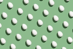 hard light pattern of a whole raw or boiled egg in egg shell on a seamless green background