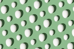 hard light pattern of a whole raw or boiled egg in egg shell on a seamless green background