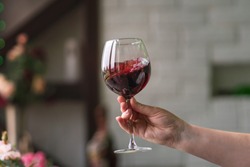 Hand sommelier holding glass of red wine. Swirling red wine glass in wine tastings. Wine tour. Space for text.
