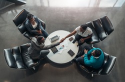 group of business people sitting and discussing statistics during a sit down meeting taking from above.