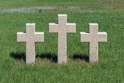 Three catholic stone crosses on young green grass at the German military cemetery in Rossoshki. Volgograd. Russia