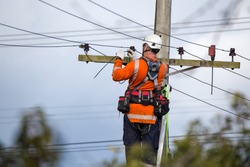A linesman with a power company connects a new house in a rural area to the main network