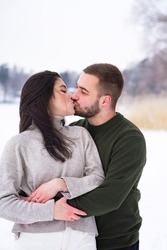 Romantic, happy couple walks in the park in winter. Man and woman hugging and kissing on valentines day. vertical frame
