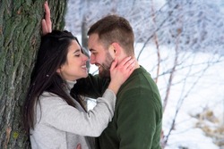 Romantic, happy couple walks in the park in winter. Man and woman hugging and kissing on valentines day. 