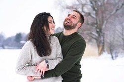 Romantic, happy couple walks in the park in winter. Man and woman hugging, laughing and smiling