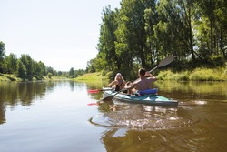 A couple of men and women kayak on the river in the summer. Active recreation, family travel, extreme adventure, sports and ecological domestic tourism. Equipment for rafting, boat, oars.