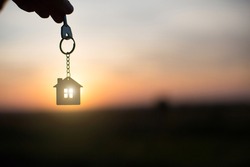 Silhouette of a house figure with a key,  keychain on the background of the sunset. They dream of a house, building, moving to a new house, mortgages, renting and buying real estate. Copy 