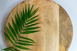 Palm leaf on wooden tray on white background. Place for text. Blank white business card mockups on wooden plate. Wooden backgound with palm leaf. Modern template. Flat lay, top 