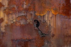 Rust of metals.Corrosive Rust on old iron with a hole. Rusted orange painted metal wall. Rusty metal background with streaks of rust. Old shabby paint.metal rust texture background