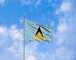 The National flag of Saint Lucia blowing in the wind in front of a clear blue sky.  