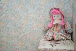 Vintage doll on a flowers wall-paper