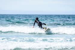 Surfer man with surfboard is falling in water. Guy in surfing wet suit is falling into the waves of cold Atlantic ocean in Galicia, Spain. Surfing accident concept.