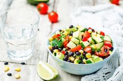 Black beans corn avocado cucumber tomato salad with lime dressing. toning. selective focus