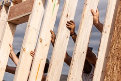 Hands of volunteers raising a wall for a Habitat for Humanity home