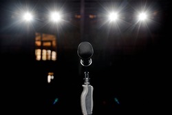Microphone on the stand with hand nozzle in the center tage with beautiful bokeh spotlights in the background. High quality photo
