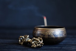 Symbols of Buddhism. Antique sound bowl and vajra on the dark table. Copy space.